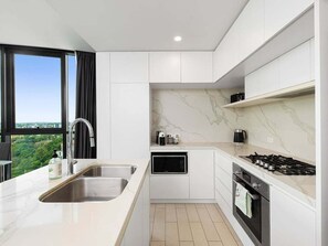Una cocina moderna con microondas, estufa y pileta, y vistas a zonas verdes.