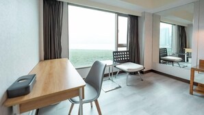 A hotel room with a large window, a wooden desk, a chair, a small table, and a mirror. - See S Revert Hotel (New Taipei City)