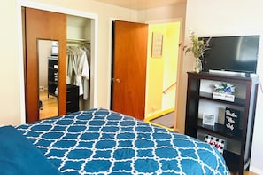 Ein Schlafzimmer mit Bett, Fernseher, Kleiderschrank und Spiegel.
