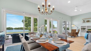 Un espace repas avec vue sur le lac, un lustre et une cuisine moderne.