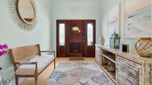 Un banc en bois, un miroir, une porte ornée d’un panneau décoratif et un tapis à motifs.