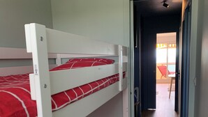A bunk bed room with a carpeted floor and a door leading to a balcony. - Appart vue mer 4 pers - comfort and beach (La Baule-Escoublac)