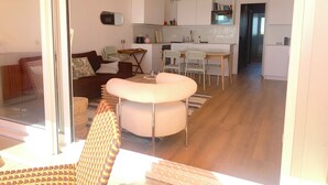 A modern living room with a sofa, ottoman, and dining area with chairs and a table. - Appart vue mer 4 pers - comfort and beach (La Baule-Escoublac)