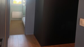 A room with a wooden floor, a bed, a window, and a door leading to another room. - Appart vue mer 4 pers - comfort and beach (La Baule-Escoublac)