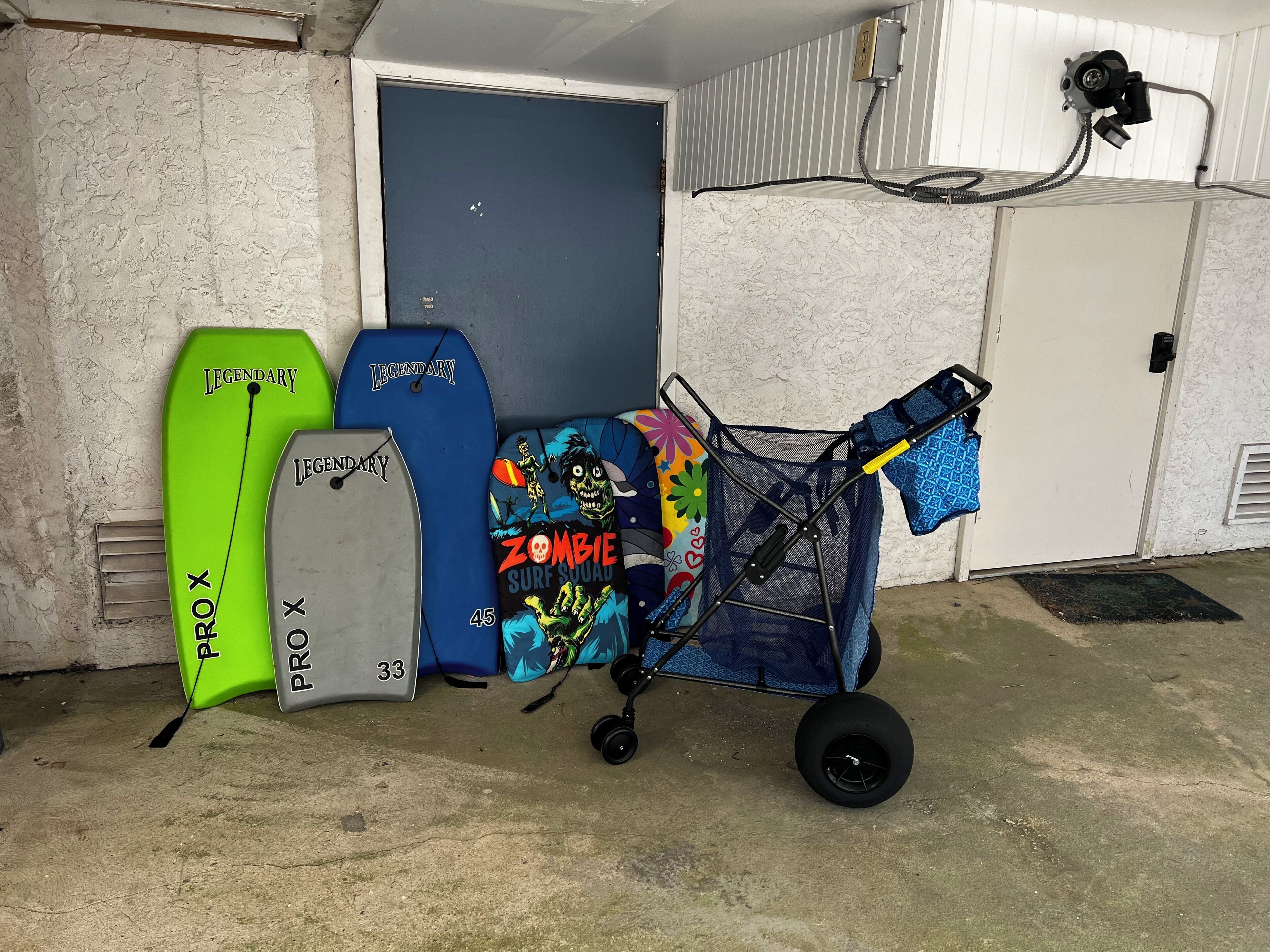 A storage area with surfboards, a cart with bags, and a door.