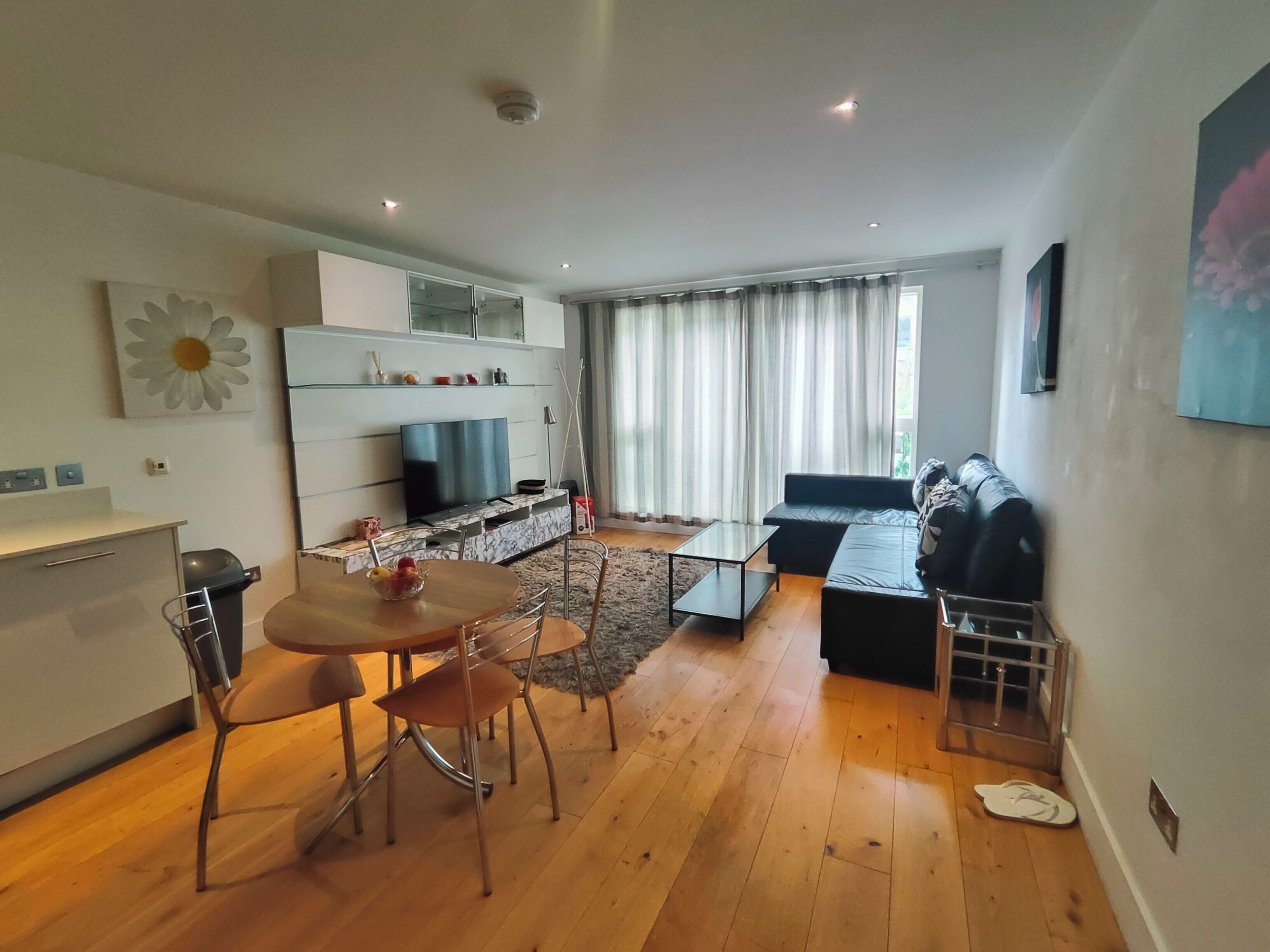A modern living space with a dining area, sofa, and a television.