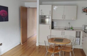 Eine kleine Küche mit Essbereich, Holzboden und weißen Schränken.