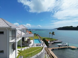 Una casa moderna con piscina, un molo e vista sull'oceano.