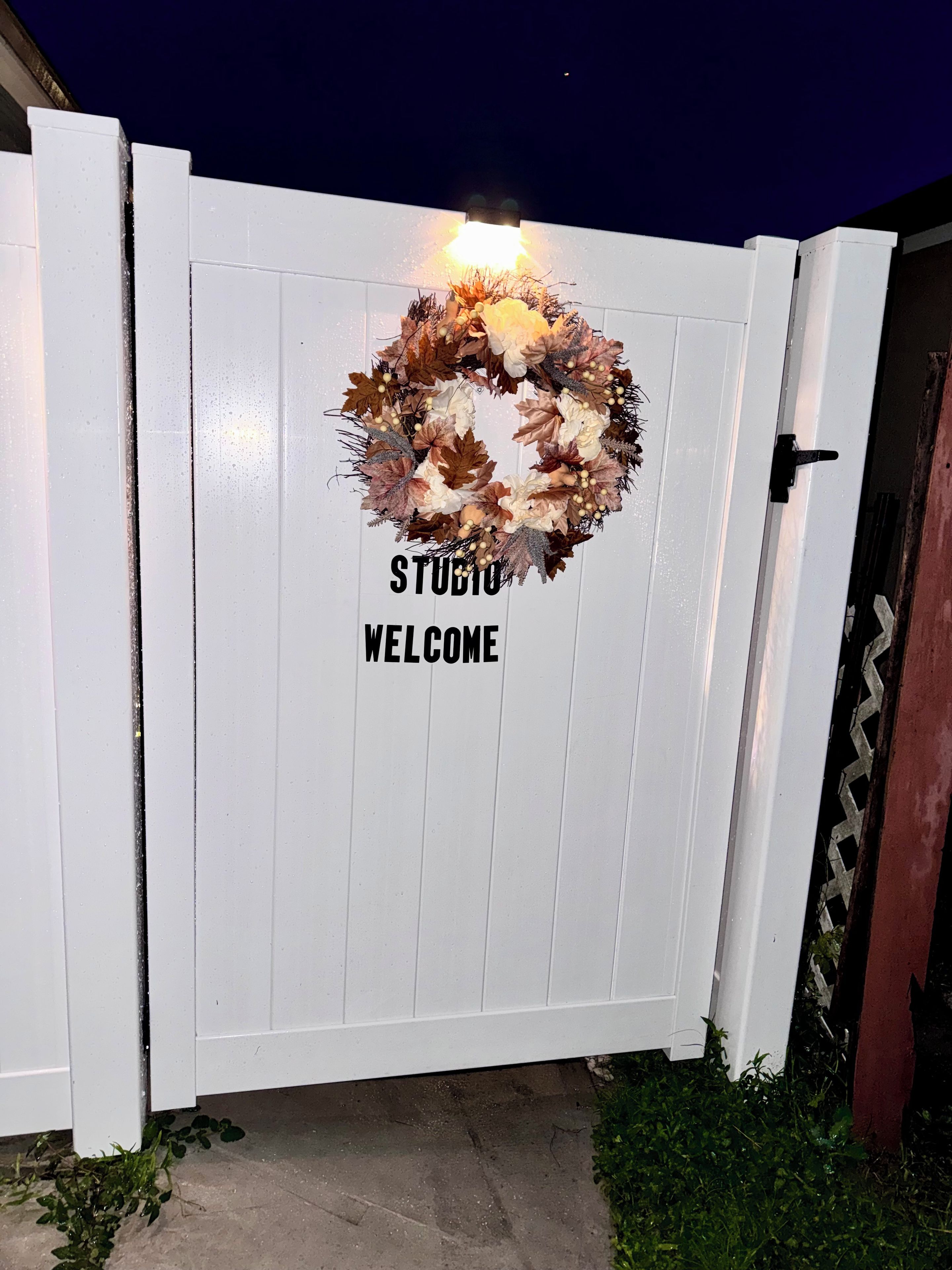 En hvid port med en krans og teksten 'STUDIO WELCOME'.