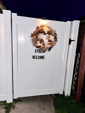 Een witte poort met een krans en de tekst 'STUDIO WELCOME'.