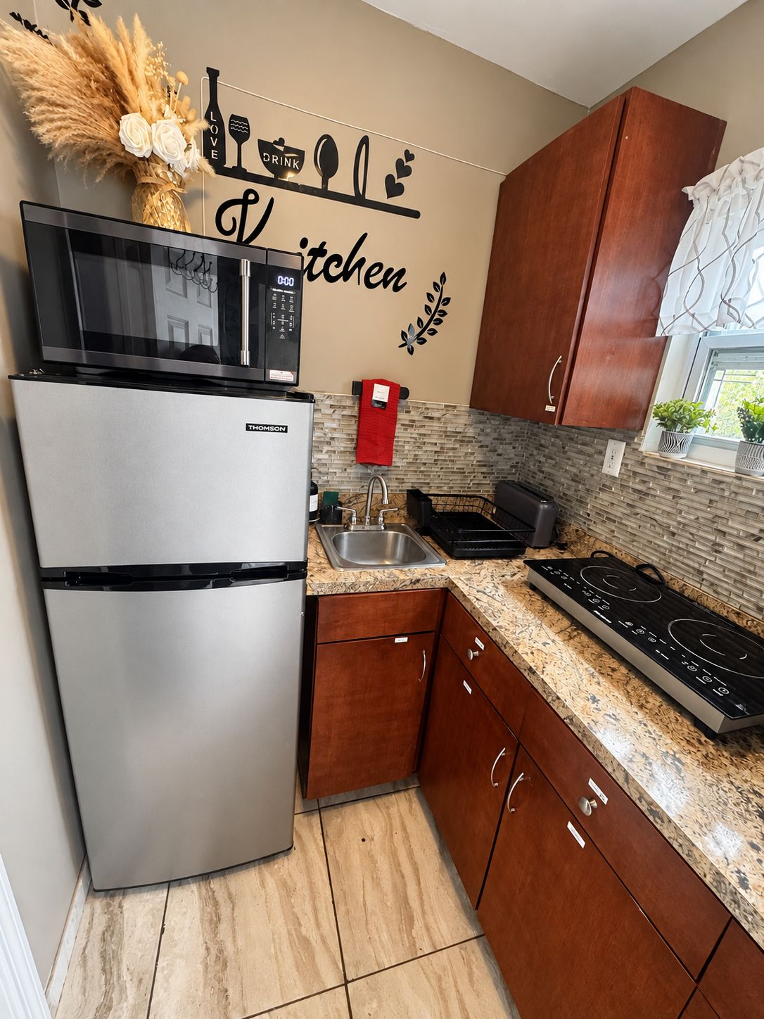 A kitchen with a stainless steel refrigerator, a microwave, a sink, and a stove.