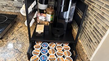En köksbänk med en kaffebryggare, en teautomat och en låda med flera behållare.