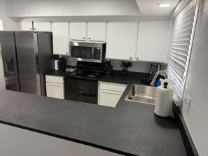 A modern kitchen with stainless steel appliances, white cabinets, and a grey countertop. - Old Town Art Stay • Luxe 3 Bedroom (Scottsdale)