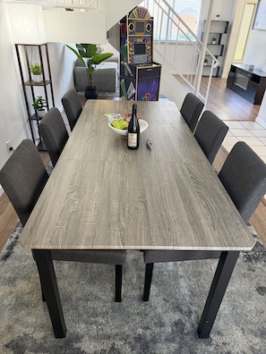 A dining table with chairs, a bottle of wine, and a bowl of snacks. - Old Town Art Stay • Luxe 3 Bedroom (Scottsdale)