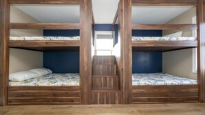 Una habitación con dos literas, una escalera de madera y vista al pasillo.