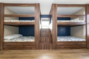 Ein Zimmer mit zwei Etagenbetten, einer Holztreppe und Blick auf den Flur.