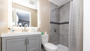 Un baño con ducha, inodoro y tocador.