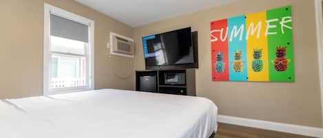 Une chambre à coucher comprenant un lit, une télévision, un four à micro-ondes et un élément de décoration murale.