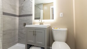 A modern bathroom with a shower, toilet, and vanity. - Adjoining Room 2 - Spacious Two-Bedroom Suite Near Seaside Heights Beach, Sleeps 10 with Free WiFi  and  AC (Seaside Heights)