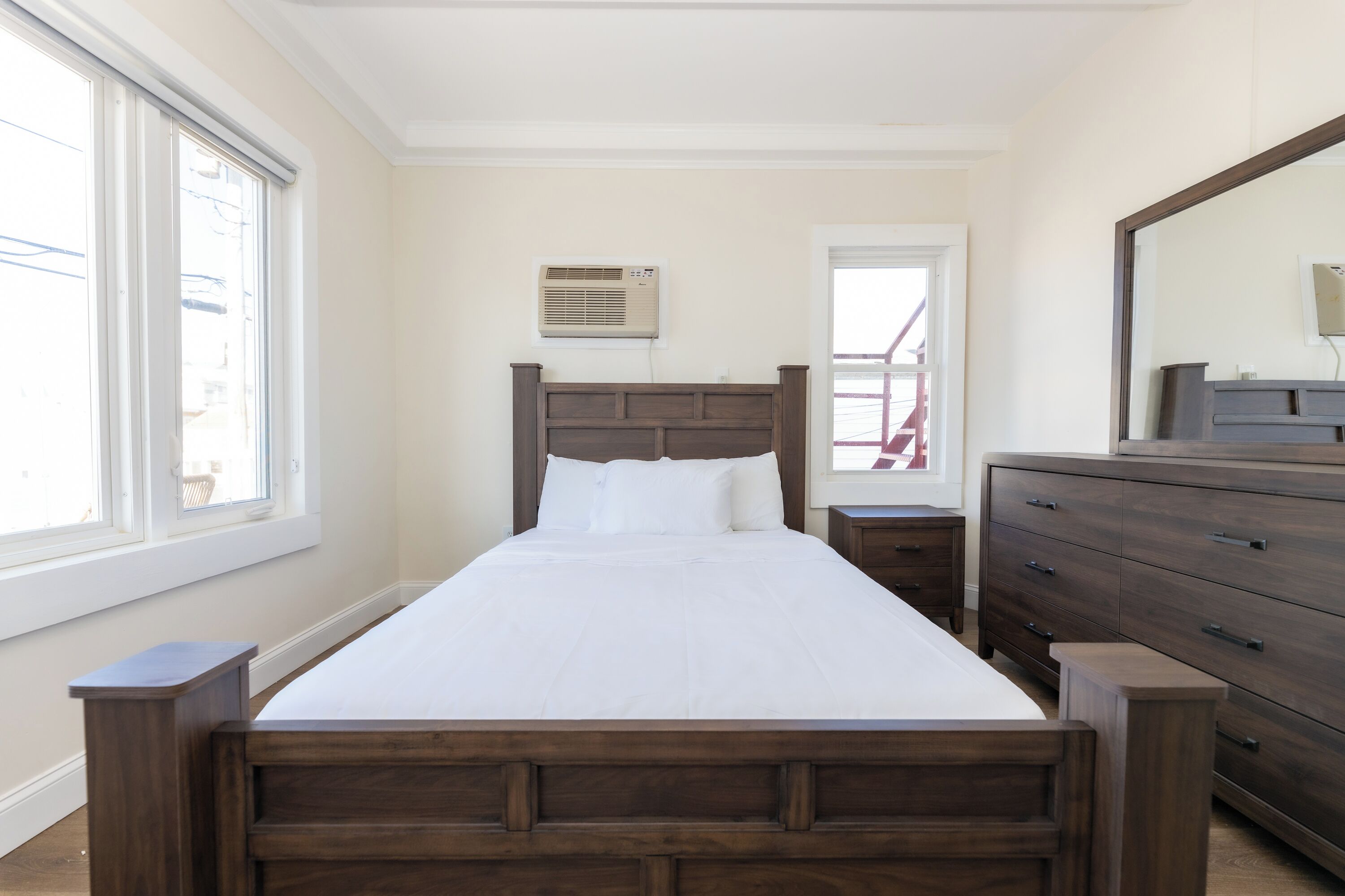 A bedroom with a wooden bed, a dresser, and a mirror.