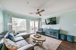 Ein Wohnzimmer mit Sofa, Couchtisch, Fernseher und Deckenventilator.