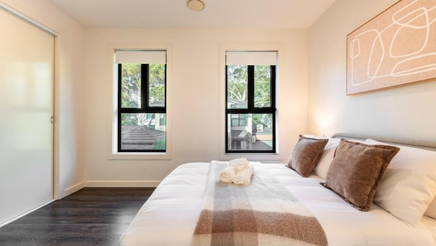Quarto com cama grande, duas janelas e um quadro na parede.