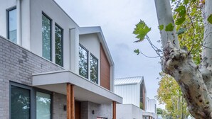 Un bâtiment moderne doté de grandes fenêtres, d’une façade en briques et d’un arbre aux feuilles vertes.