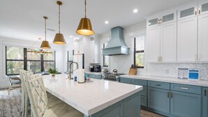 Een moderne keuken met een groot eiland, witte kasten en blauwe accenten.