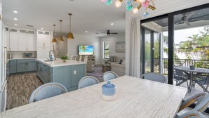 Een moderne keuken met witte kastjes, een inbouwoven, en een eethoek met tafel en stoelen.