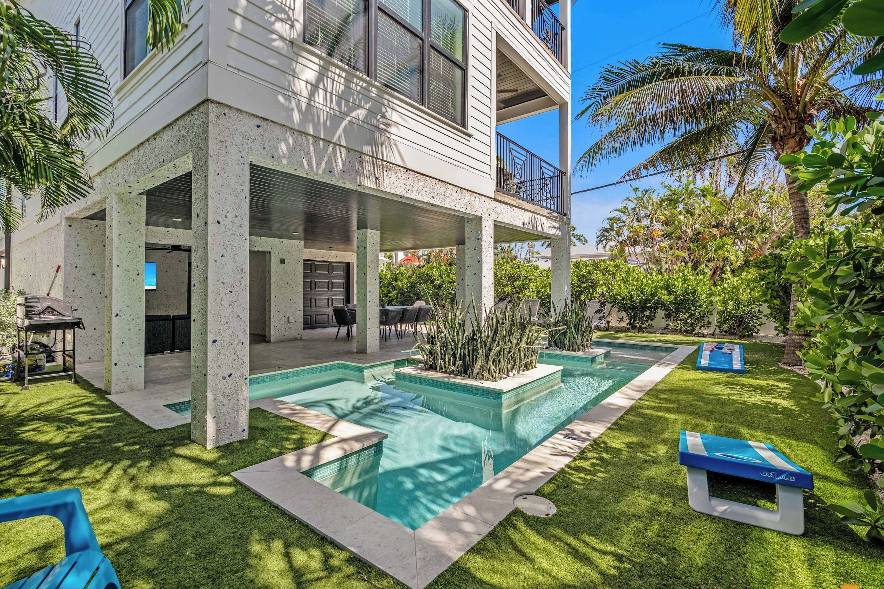 A two-story house with a covered patio, a swimming pool, and a well-maintained garden.