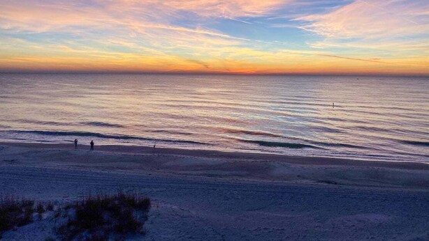 Een strand met een heldere lucht en een rustige zee.