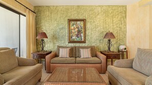Ein Wohnzimmer mit einer Couch, zwei Sesseln, einem Couchtisch und zwei Lampen.