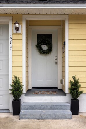A yellow house with a white door, number 874, a black mailbox, and two potted plants. - St. Augustine 3BR • Game Room, Fire Pit, Beach & Old City • Sleeps 8 (St. Augustine)