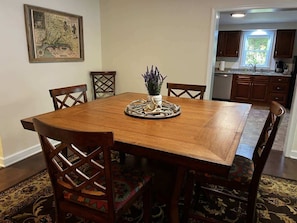 Comedor con mesa de madera, sillas, un centro de mesa decorativo y un mapa en la pared.