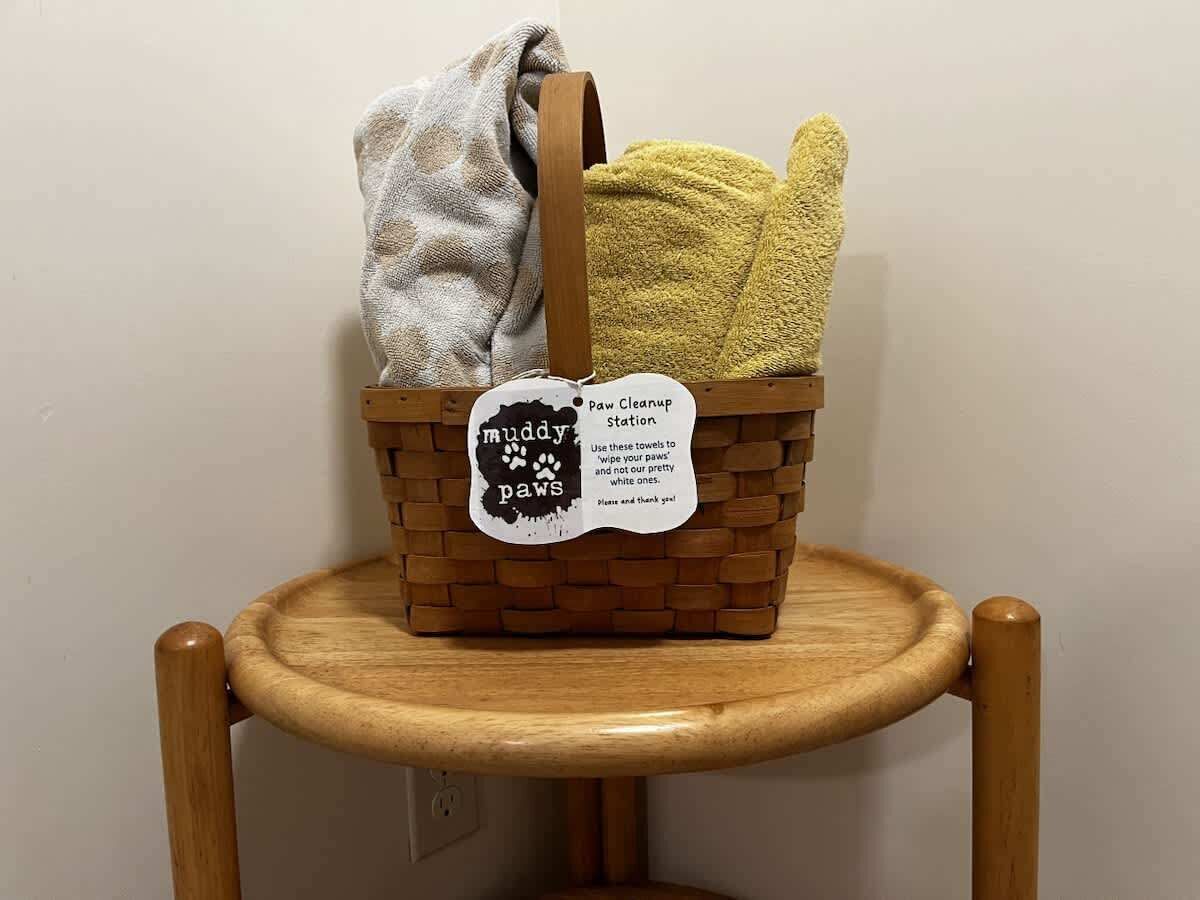 A wicker basket with a tag labeled 'muddy paws' on a wooden chair.