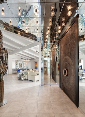 Ein modernes Interieur mit einer zentralen Sitzecke, einer Wand mit Muster und hängenden Leuchten.