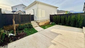 A residential property with a detached house, a fenced backyard, and a paved driveway.