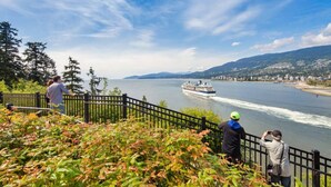A waterfront view with a cruise ship, a cityscape, and a forested area. - FIFA Stay 1BR| Steps to Seawall | Free Parking+AC (Vancouver)