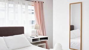 A hotel room with a bed, bedside table, lamp, and a large mirror.