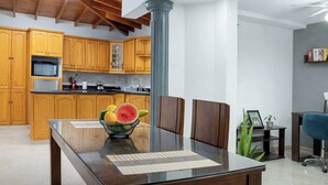 A modern kitchen with wooden cabinets, a central column, and a dining table with chairs.
