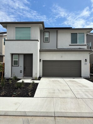 A two-story residential building with a garage, a front door, and a small window on the upper floor. - Sequoia Arcade House - New Build - Sleeps 10 (Visalia)