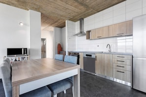 Uma cozinha moderna com mesa de jantar de madeira, eletrodomésticos embutidos e painel de azulejos.