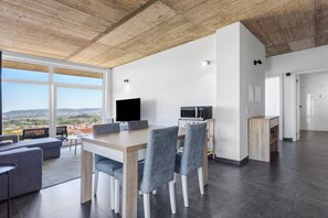 Um espaço de estar moderno com área de jantar, televisão de tela plana e vista para a paisagem.