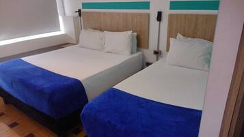 Two single beds with blue bedspreads, wooden headboards, and white bedding.