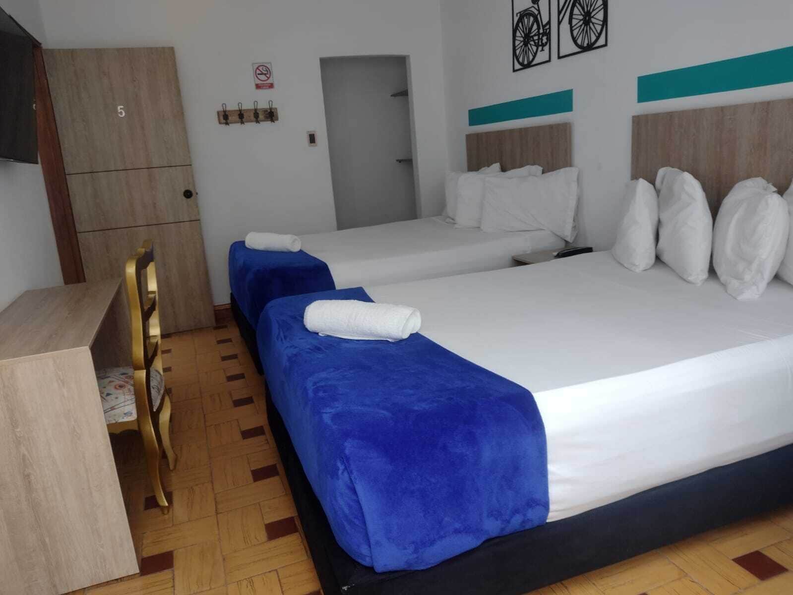 Une chambre d’hôtel avec deux lits, un bureau et une armoire.