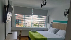 A room with a bed, two bedside tables, a chair, a desk, and a window with a view. - hotel boutique casa vecchia  (Cali)