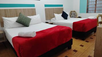 Une chambre d’hôtel avec deux lits, chacun recouvert d’une couverture rouge et doté d’oreillers blancs, ainsi qu’une tête de lit en bois et une fenêtre donnant sur un paysage agréable.
