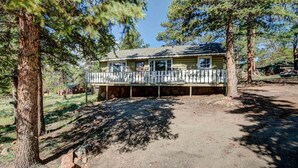 A two-story house with a balcony, surrounded by trees. - Crooked Pine Cottage- Close To RMNP Entrance (Estes Park)