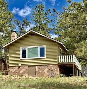 A single-story house with a stone foundation, a large window, and a porch. - Crooked Pine Cottage- Close To RMNP Entrance (Estes Park)