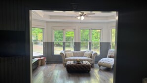Ein Zimmer mit großem Fenster, Deckenventilator und Holzboden.
